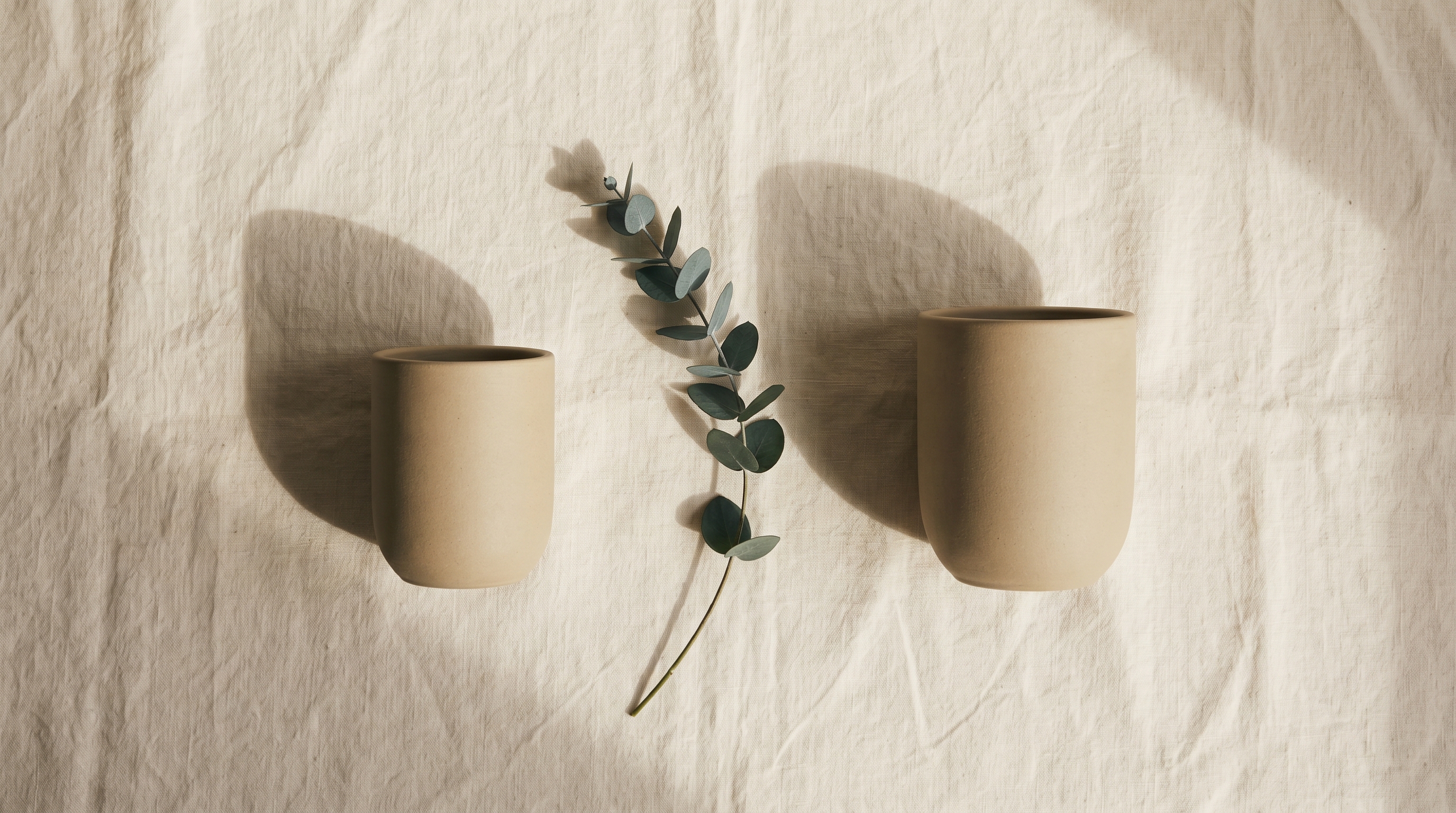 Two identical-looking matte ceramic vessels placed symmetrically on linen, visual metaphor for the clinical sameness behind the Korean-vs-Allergan price gap