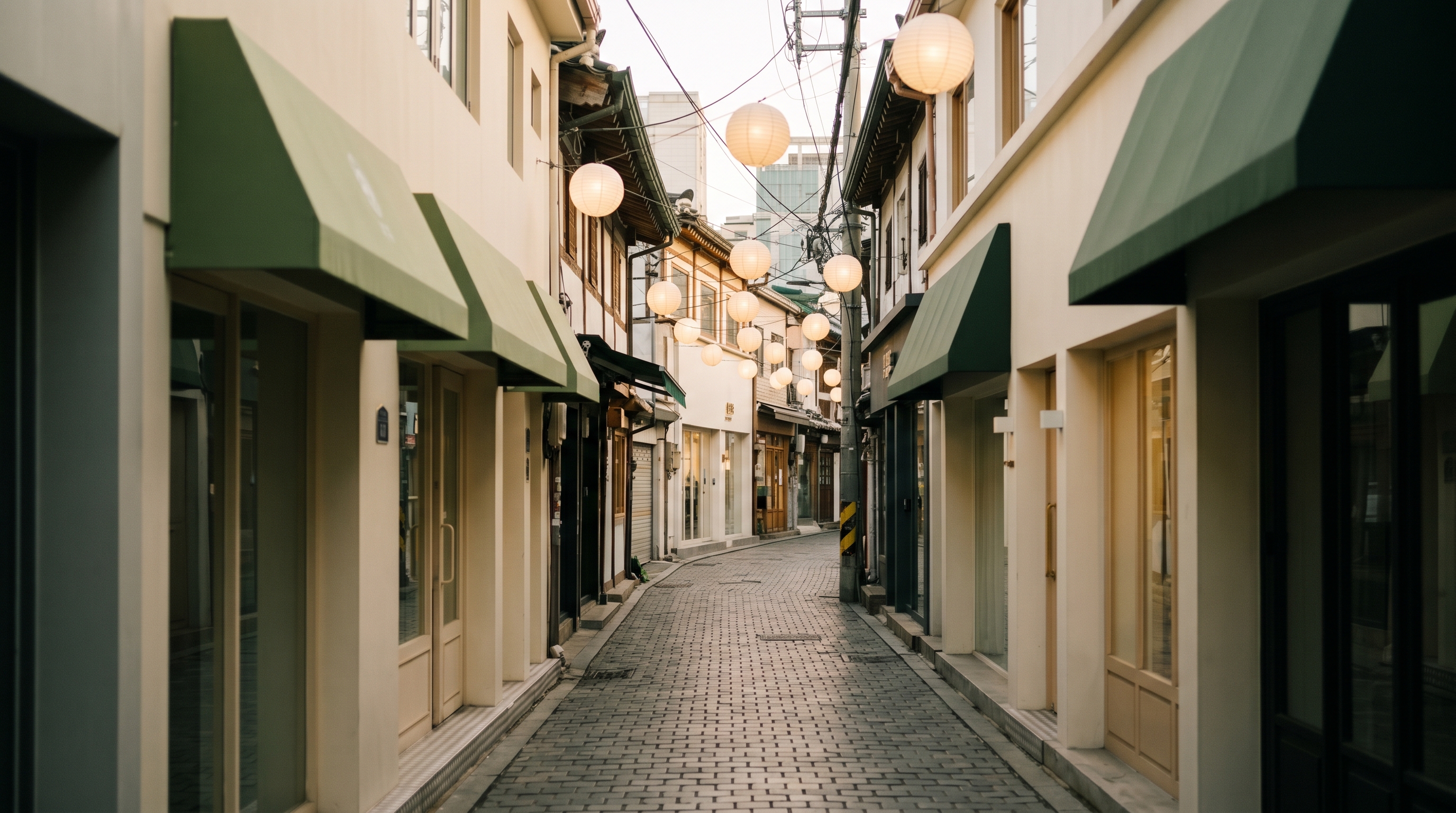 Central Seoul pedestrian shopping alley at early evening with hanging spherical paper lanterns, calm-just-before-the-crowds mood for Myeongdong